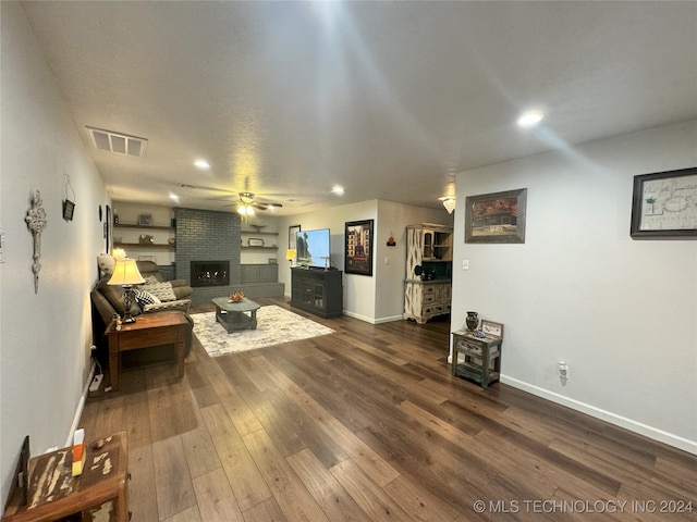 living room with ceiling fan, a fireplace, and dark hardwood / wood-style flooring