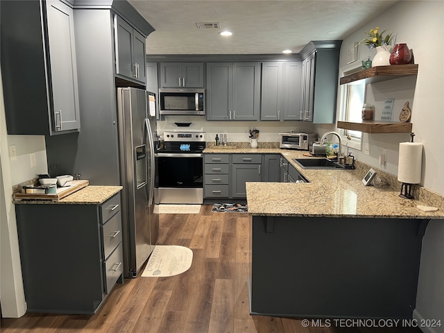 kitchen featuring sink, kitchen peninsula, gray cabinetry, dark wood-type flooring, and appliances with stainless steel finishes