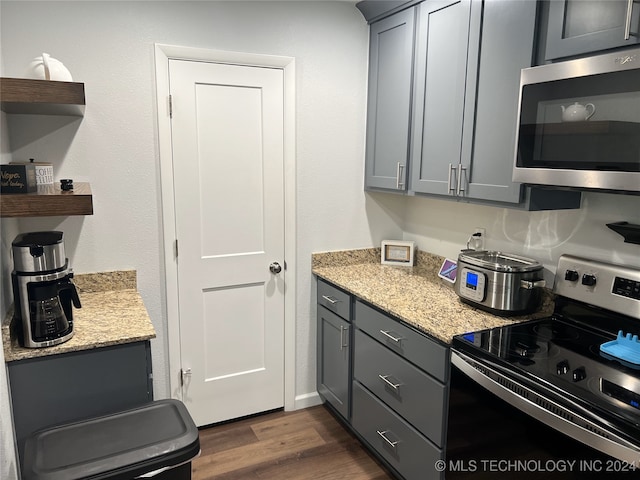 kitchen featuring gray cabinets, appliances with stainless steel finishes, dark hardwood / wood-style floors, and light stone countertops