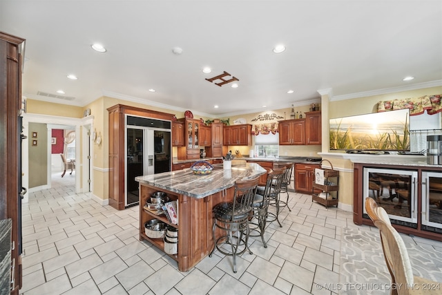 kitchen featuring beverage cooler, a center island, a kitchen breakfast bar, built in refrigerator, and crown molding