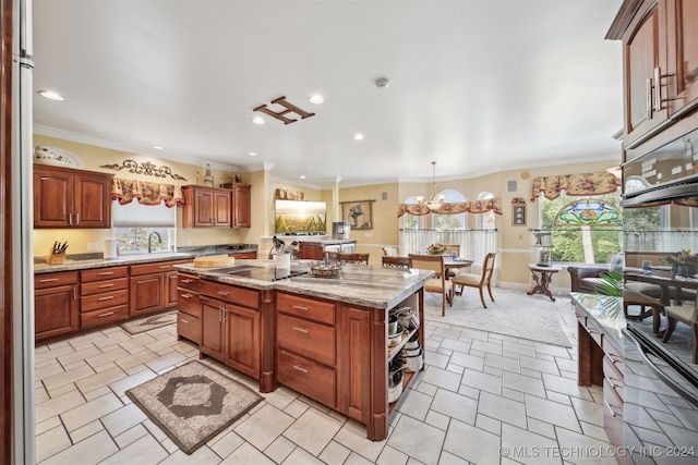 kitchen featuring black electric stovetop, ornamental molding, a center island, decorative light fixtures, and light stone counters