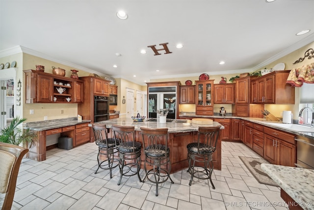 kitchen with sink, a kitchen island, ornamental molding, a breakfast bar area, and black double oven