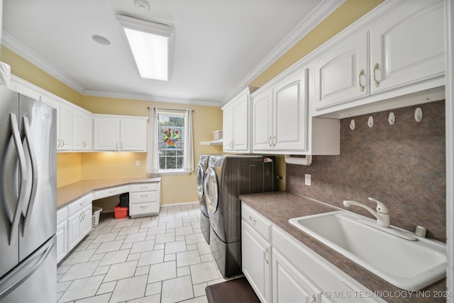 clothes washing area featuring sink, crown molding, separate washer and dryer, and cabinets