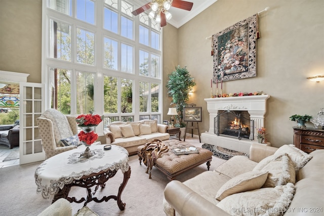 living room with ceiling fan, crown molding, and a high ceiling