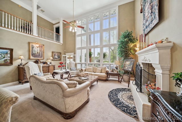 living room with a high ceiling, light carpet, crown molding, and ceiling fan