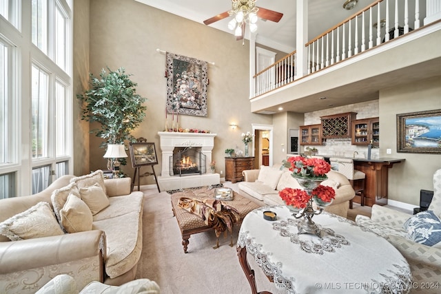 living room with ceiling fan, carpet, and a high ceiling