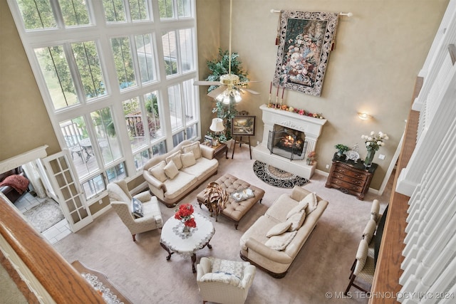 living room featuring ceiling fan, carpet, and a high ceiling