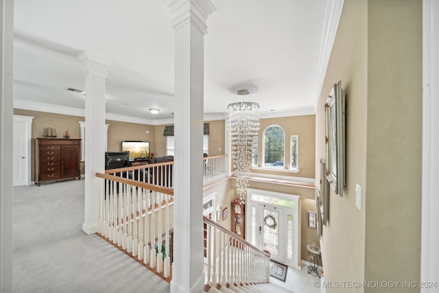 stairs featuring ornamental molding, ornate columns, carpet floors, and an inviting chandelier