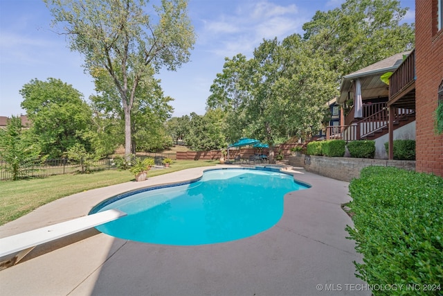 view of swimming pool with a yard, a diving board, and a patio