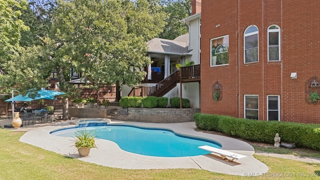 view of swimming pool with a patio, a lawn, and a diving board