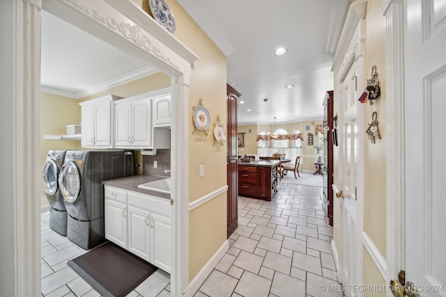 kitchen with tasteful backsplash, white cabinetry, washer and dryer, ornamental molding, and sink