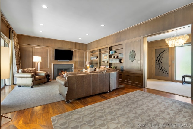 living room featuring an inviting chandelier, wooden walls, and hardwood / wood-style floors