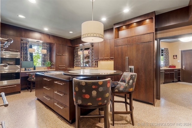 kitchen featuring a kitchen breakfast bar, stainless steel appliances, pendant lighting, dark brown cabinetry, and a center island