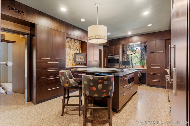 kitchen featuring a kitchen island, a breakfast bar area, dark brown cabinetry, decorative light fixtures, and appliances with stainless steel finishes