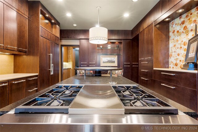 kitchen featuring range, decorative light fixtures, and paneled built in refrigerator