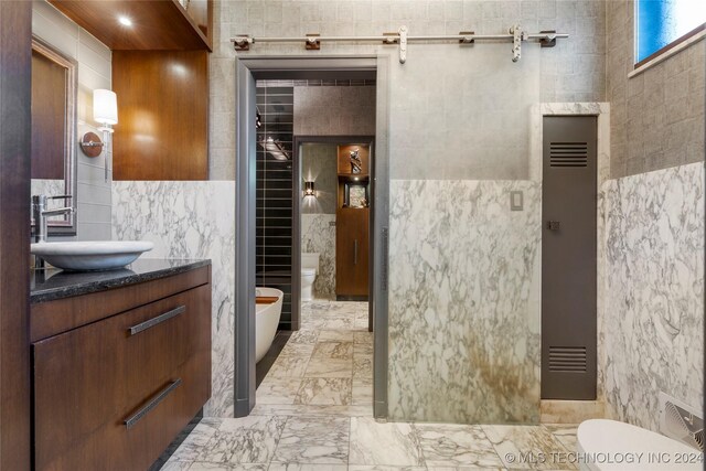 bathroom featuring tile walls, vanity, elevator, and toilet