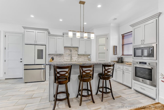 kitchen featuring a kitchen bar, built in appliances, light stone counters, and decorative light fixtures