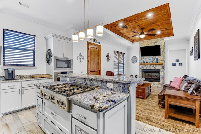 kitchen with a kitchen island, a raised ceiling, ornamental molding, stainless steel appliances, and wooden ceiling