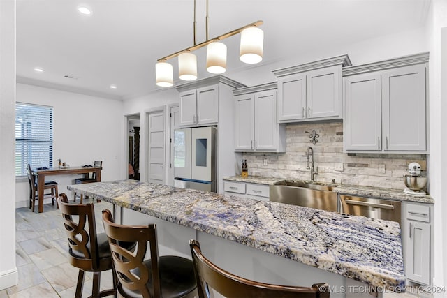 kitchen with sink, gray cabinetry, tasteful backsplash, fridge, and a kitchen breakfast bar