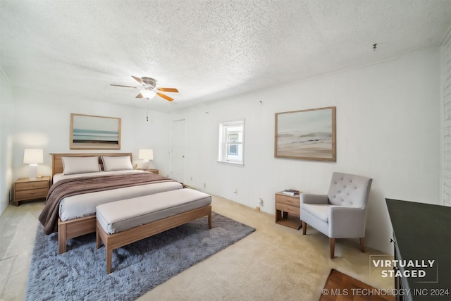 bedroom featuring ceiling fan, light colored carpet, and a textured ceiling