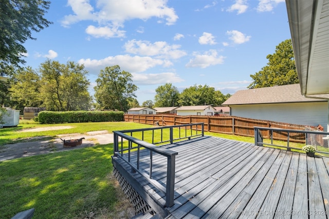 wooden terrace with an outdoor fire pit and a lawn