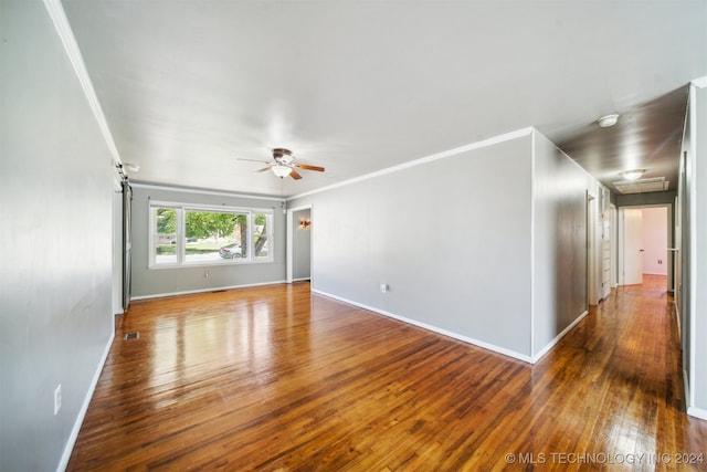 unfurnished room featuring crown molding, dark wood-type flooring, ceiling fan, and a barn door