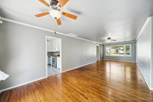 unfurnished living room featuring ceiling fan, crown molding, and wood-type flooring