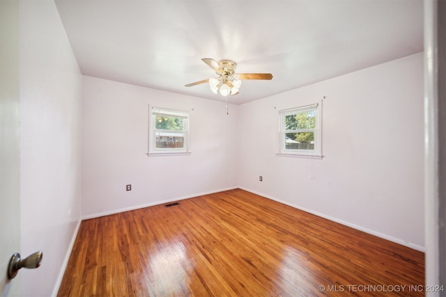 spare room featuring a wealth of natural light, ceiling fan, and hardwood / wood-style floors