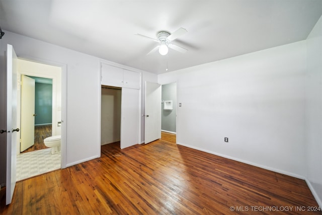 unfurnished bedroom featuring connected bathroom, hardwood / wood-style floors, ceiling fan, and a closet