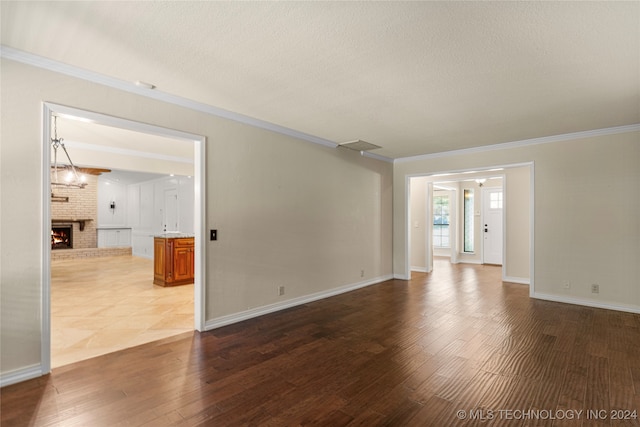 spare room with a fireplace, dark hardwood / wood-style floors, ornamental molding, and a textured ceiling