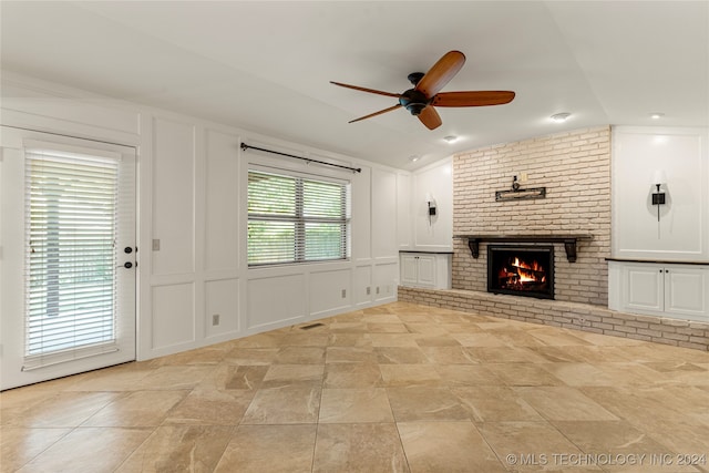 unfurnished living room with lofted ceiling, ceiling fan, and a brick fireplace