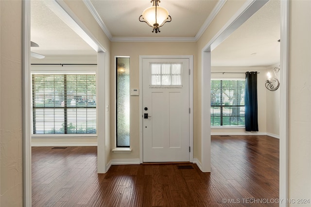 entryway with dark wood-type flooring, a textured ceiling, and ornamental molding