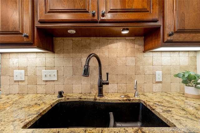 kitchen with light stone counters, tasteful backsplash, and sink