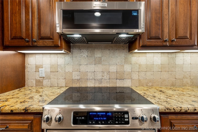 kitchen with light stone countertops, appliances with stainless steel finishes, and tasteful backsplash