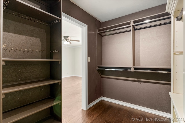 spacious closet with dark wood-type flooring and ceiling fan