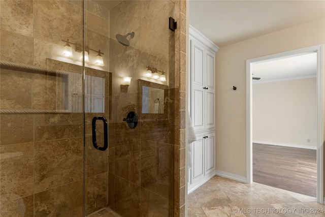 bathroom with crown molding, hardwood / wood-style flooring, and a shower with shower door