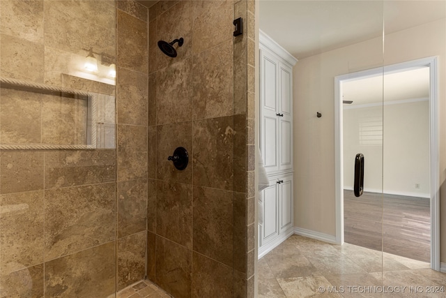 bathroom with a tile shower and ornamental molding