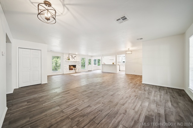 unfurnished living room featuring a notable chandelier, a high end fireplace, and dark hardwood / wood-style flooring