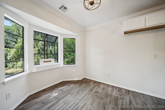 spare room with ornamental molding, plenty of natural light, and hardwood / wood-style floors