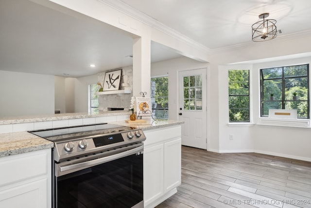 kitchen with a wealth of natural light, stainless steel electric range, white cabinetry, and light wood-type flooring