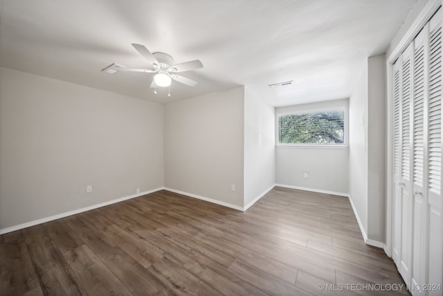 unfurnished bedroom with ceiling fan, a closet, and dark hardwood / wood-style flooring