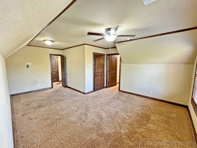 bonus room with a textured ceiling, light colored carpet, vaulted ceiling, and ceiling fan