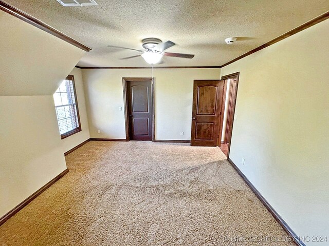 interior space with a textured ceiling, ceiling fan, ornamental molding, and light carpet