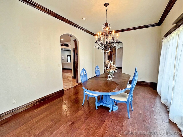 dining space featuring crown molding, hardwood / wood-style floors, and an inviting chandelier