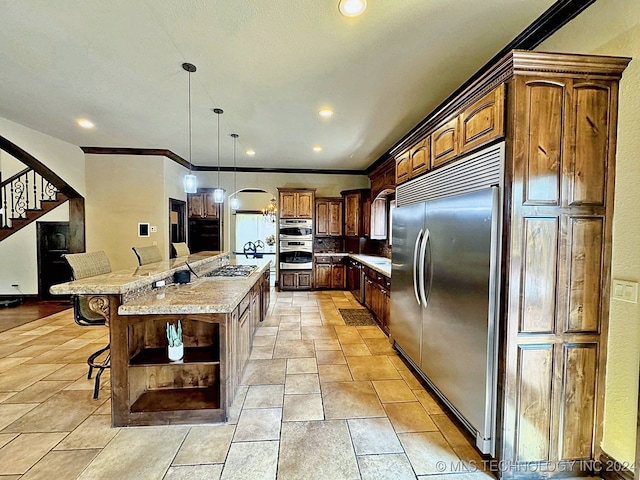 kitchen featuring ornamental molding, light stone counters, a breakfast bar, appliances with stainless steel finishes, and a large island