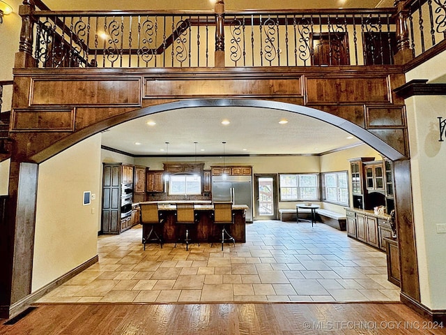 interior space featuring a kitchen island, a kitchen breakfast bar, built in refrigerator, light hardwood / wood-style floors, and ornamental molding