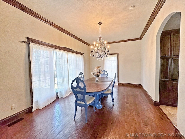 dining space featuring hardwood / wood-style floors, ornamental molding, a notable chandelier, and a textured ceiling