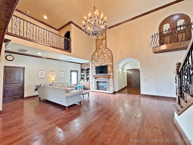 living room with dark wood-type flooring, a fireplace, ornamental molding, and a towering ceiling