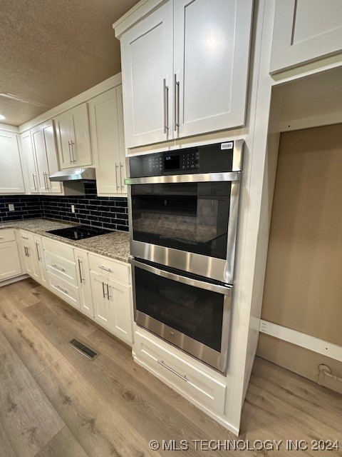 kitchen featuring white cabinets, black electric stovetop, and stainless steel double oven