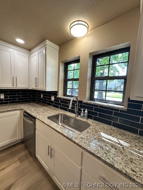 kitchen featuring light hardwood / wood-style flooring, stainless steel dishwasher, white cabinetry, and sink